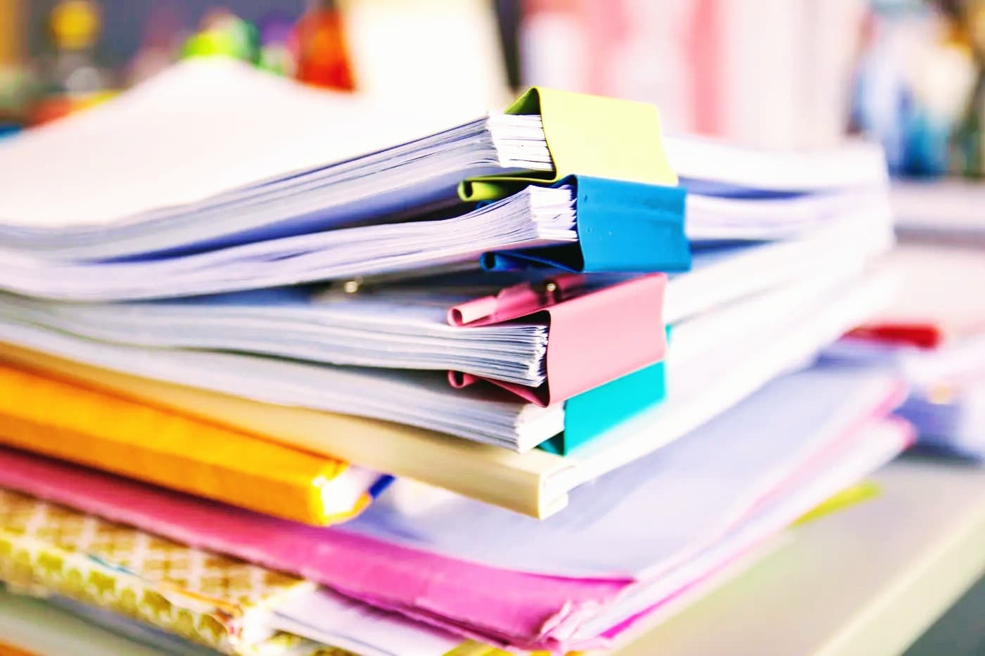 Stack of white papers organized with vibrant yellow, blue, and pink binder clips.