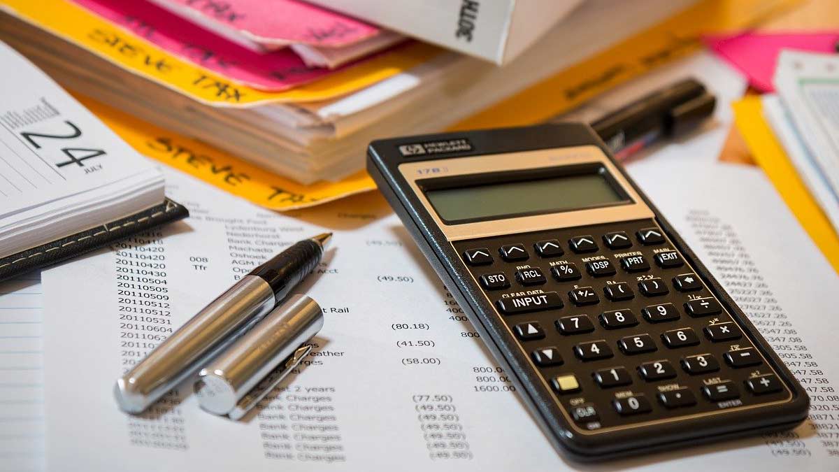 Silver fountain pen and financial calculator resting on a desk cluttered with business documents.